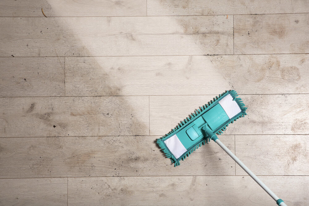 A person cleaning dirty hardwood floors.